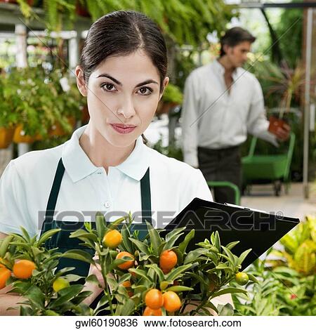 Stock Photograph - Portrait of a woman in a greenhouse. Fotosearch