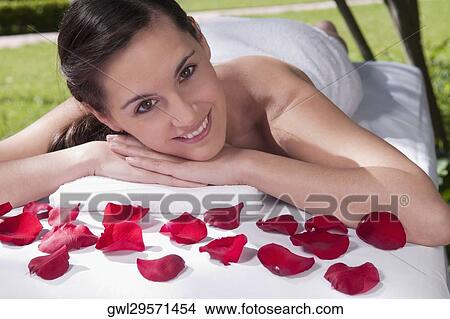 Portrait of a woman lying on a massage table with rose petals View Large Photo Image Picture - Portrait of a woman lying on a massage table with rose petals. Fotosearch
