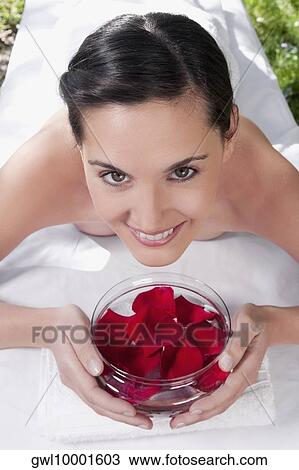 Portrait of a woman lying on a massage table holding a bowl of rose petals View Large Photo Image Stock Image - Portrait of a woman lying on a massage table holding a bowl of rose petals. Fotosearch