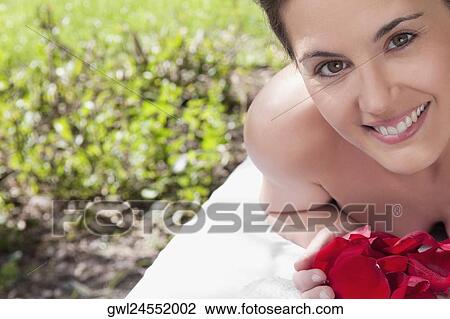 Portrait of a woman lying on a massage table holding rose petals View Large Photo Image Stock Image - Portrait of a woman lying on a massage table holding rose petals. Fotosearch