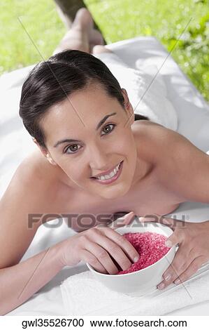 Portrait of a woman lying on a massage table and holding a bowl of bath salt View Large Photo Image Stock Image - Portrait of a woman lying on a massage table and holding a bowl of bath salt. Fotosearch