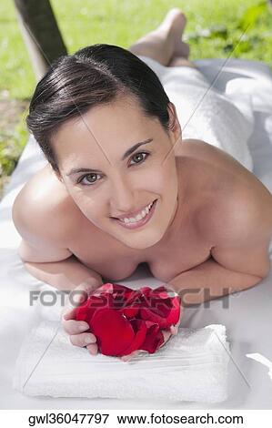 Portrait of a woman lying on a massage table holding rose petals View Large Photo Image Stock Photo - Portrait of a woman lying on a massage table holding rose petals. Fotosearch