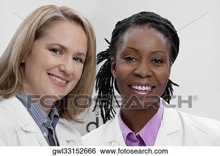 Stock Photograph - Portrait of two female doctors smiling. Fotosearch