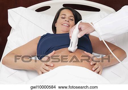Pregnant woman going through an ultrasound scan View Large Photo Image Picture - Pregnant woman going through an ultrasound scan. Fotosearch