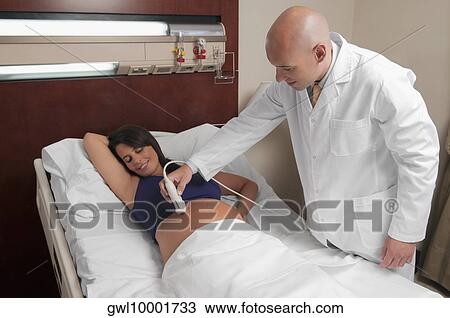 Stock Image - Pregnant woman going through an ultrasound scan. Fotosearch