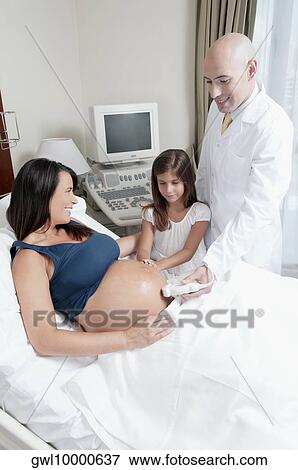 Pregnant woman going through an ultrasound scan with her daughter looking at her View Large Photo Image Stock Photo - Pregnant woman going through an ultrasound scan with her daughter looking at her. Fotosearch