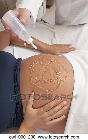 Pregnant woman going through an ultrasound scan View Large Photo Image Stock Photo - Pregnant woman going through an ultrasound scan. Fotosearch