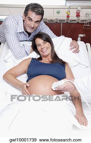 Pregnant woman going through an ultrasound scan View Large Photo Image Stock Photo - Pregnant woman going through an ultrasound scan. Fotosearch