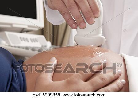 Pregnant woman going through an ultrasound scan View Large Photo Image Stock Photo - Pregnant woman going through an ultrasound scan. Fotosearch