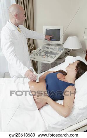 Pregnant woman going through an ultrasound scan View Large Photo Image Stock Photo - Pregnant woman going through an ultrasound scan. Fotosearch