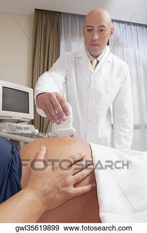 Pregnant woman going through an ultrasound scan View Large Photo Image Stock Photo - Pregnant woman going through an ultrasound scan. Fotosearch