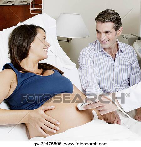 Pregnant woman going through an ultrasound scan with her husband beside her View Large Photo Image Stock Photograph - Pregnant woman going through an ultrasound scan with her husband beside her. Fotosearch