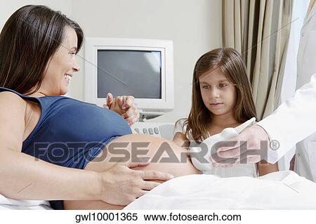 Pregnant woman going through an ultrasound scan with her daughter looking at her View Large Photo Image Stock Photography - Pregnant woman going through an ultrasound scan with her daughter looking at her. Fotosearch