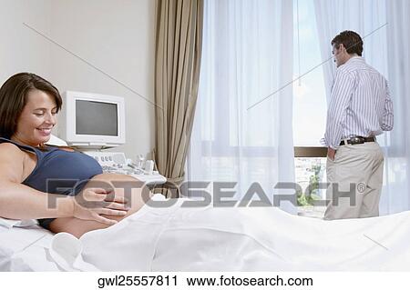 Pregnant woman in a hospital with her husband looking out through a window View Large Photo Image Stock Image - Pregnant woman in a hospital with her husband looking out through a window. Fotosearch