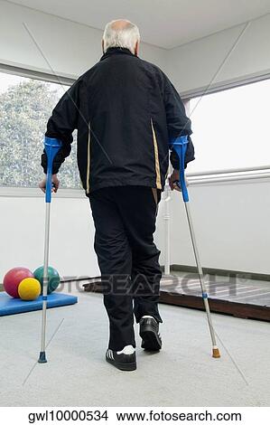 Rear view of a disabled man walking with the help of crutches View Large Photo Image Picture - Rear view of a disabled man walking with the help of crutches. Fotosearch