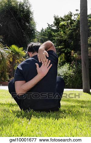 Rear view of a man exercising in a park View Large Photo Image Stock Photo - Rear view of a man exercising in a park. Fotosearch