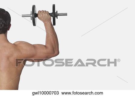 Rear view of a man exercising with a dumbbell View Large Photo Image Stock Image - Rear view of a man exercising with a dumbbell. Fotosearch