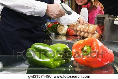 Stock Image - Sales clerk scanning price of eggs with a bar code reader. Fotosearch