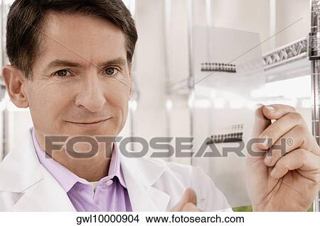 Scientist examining a report in a laboratory View Large Photo Image Picture - Scientist examining a report in a laboratory. Fotosearch