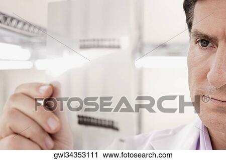 Scientist examining a report in a laboratory View Large Photo Image Stock Image - Scientist examining a report in a laboratory. Fotosearch