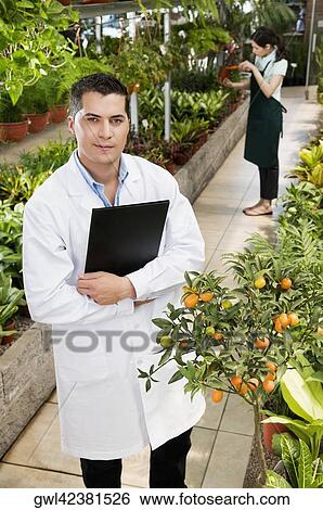 Scientist holding a clipboard in a greenhouse View Large Photo Image Stock Photograph - Scientist holding a clipboard in a greenhouse. Fotosearch