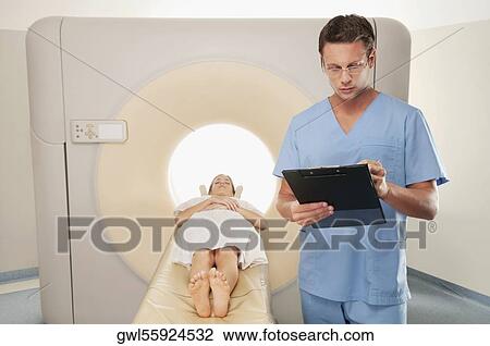 Surgeon checking medical report with a patient undergoing an MRI scan View Large Photo Image Stock Image - Surgeon checking medical report with a patient undergoing an MRI scan. Fotosearch