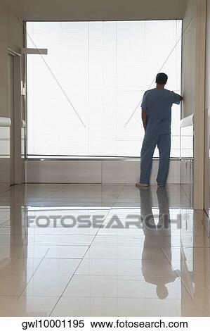Surgeon looking through a window in a hospital View Large Photo Image Stock Photography - Surgeon looking through a window in a hospital. Fotosearch