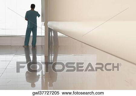 Surgeon looking through a window in a hospital View Large Photo Image Stock Photography - Surgeon looking through a window in a hospital. Fotosearch