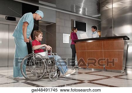 Surgeon pushing a patient in a wheelchair View Large Photo Image Stock Photography - Surgeon pushing a patient in a wheelchair. Fotosearch