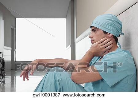 Surgeon sitting on the floor looking serious View Large Photo Image Stock Photo - Surgeon sitting on the floor looking serious. Fotosearch