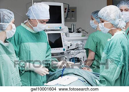 Surgeons performing a surgery in an operating room View Large Photo Image Picture - Surgeons performing a surgery in an operating room. Fotosearch