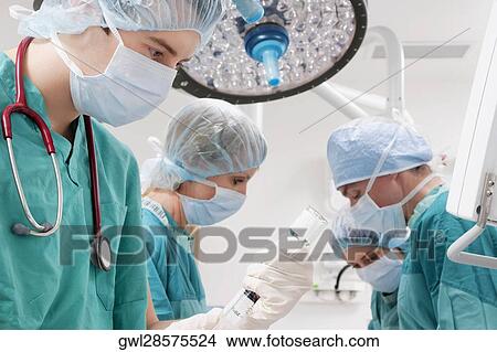 Picture - Surgeons performing a surgery in an operating room. Fotosearch
