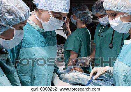Surgeons performing a surgery in an operating room View Large Photo Image Stock Image - Surgeons performing a surgery in an operating room. Fotosearch