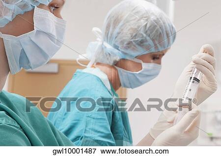 Surgeons performing a surgery in an operating room View Large Photo Image Stock Photo - Surgeons performing a surgery in an operating room. Fotosearch