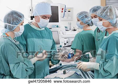 Stock Photograph - Surgeons performing a surgery in an operating room. Fotosearch