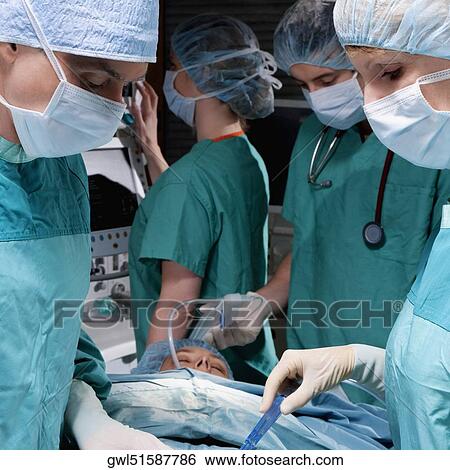 Stock Photograph - Surgeons performing a surgery in an operating room. Fotosearch