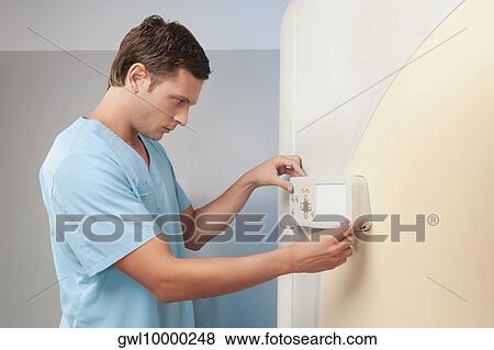 Technician operating an MRI scanner View Large Photo Image Stock Photo - Technician operating an MRI scanner. Fotosearch