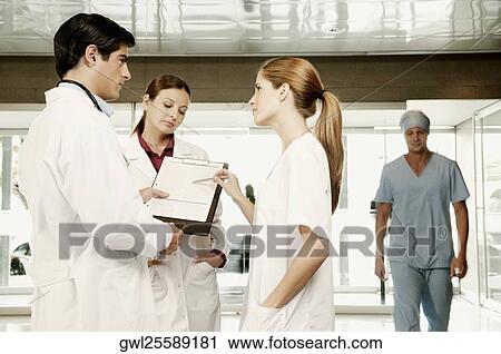 Three doctors discussing a clipboard View Large Photo Image Stock Image - Three doctors discussing a clipboard. Fotosearch