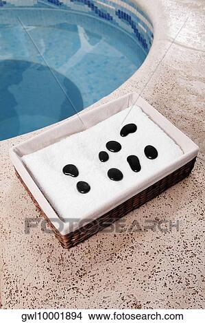 Towel and pebbles in a basket beside a hot tub View Large Photo Image Picture - Towel and pebbles in a basket beside a hot tub. Fotosearch