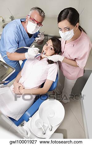 Two dentists examining a woman's teeth View Large Photo Image Stock Photo - Two dentists examining a woman's teeth. Fotosearch