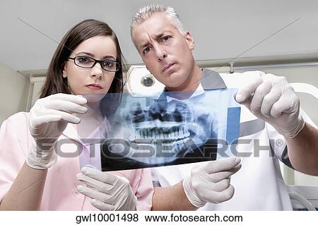 Two dentists examining an X-Ray report View Large Photo Image Stock Photo - Two dentists examining an X-Ray report. Fotosearch