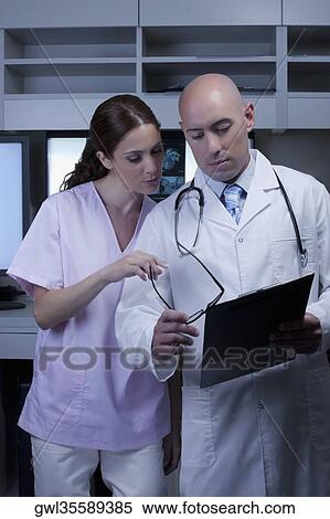 Two doctors discussing a medical report View Large Photo Image Stock Photography - Two doctors discussing a medical report. Fotosearch