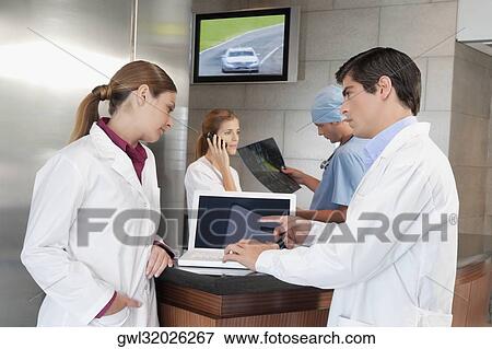 Two doctors discussing while using a laptop View Large Photo Image Stock Photo - Two doctors discussing while using a laptop. Fotosearch