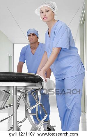 Two doctors pushing a gurney in a hospital corridor View Large Photo Image Stock Photo - Two doctors pushing a gurney in a hospital corridor. Fotosearch