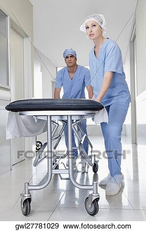 Two doctors pushing a gurney in a hospital corridor View Large Photo Image Stock Photo - Two doctors pushing a gurney in a hospital corridor. Fotosearch