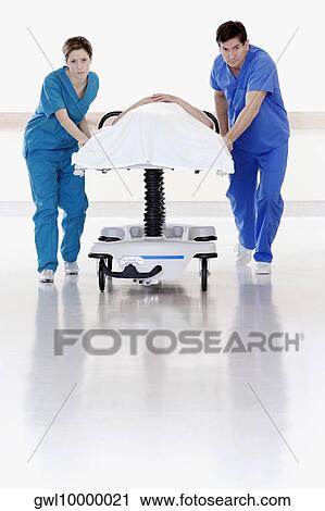 Two doctors pushing patient on a gurney View Large Photo Image Stock Image - Two doctors pushing patient on a gurney. Fotosearch