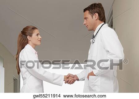 Two doctors shaking hands in a hospital corridor View Large Photo Image Picture - Two doctors shaking hands in a hospital corridor. Fotosearch