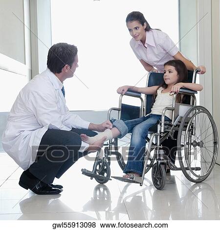 Two doctors with a patient sitting in a wheelchair View Large Photo Image Stock Photo - Two doctors with a patient sitting in a wheelchair. Fotosearch