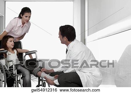 Two doctors with a patient sitting in a wheelchair View Large Photo Image Stock Photograph - Two doctors with a patient sitting in a wheelchair. Fotosearch