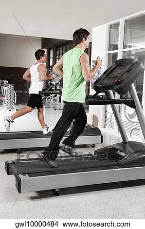 Two men running on treadmills View Large Photo Image Picture - Two men running on treadmills. Fotosearch
